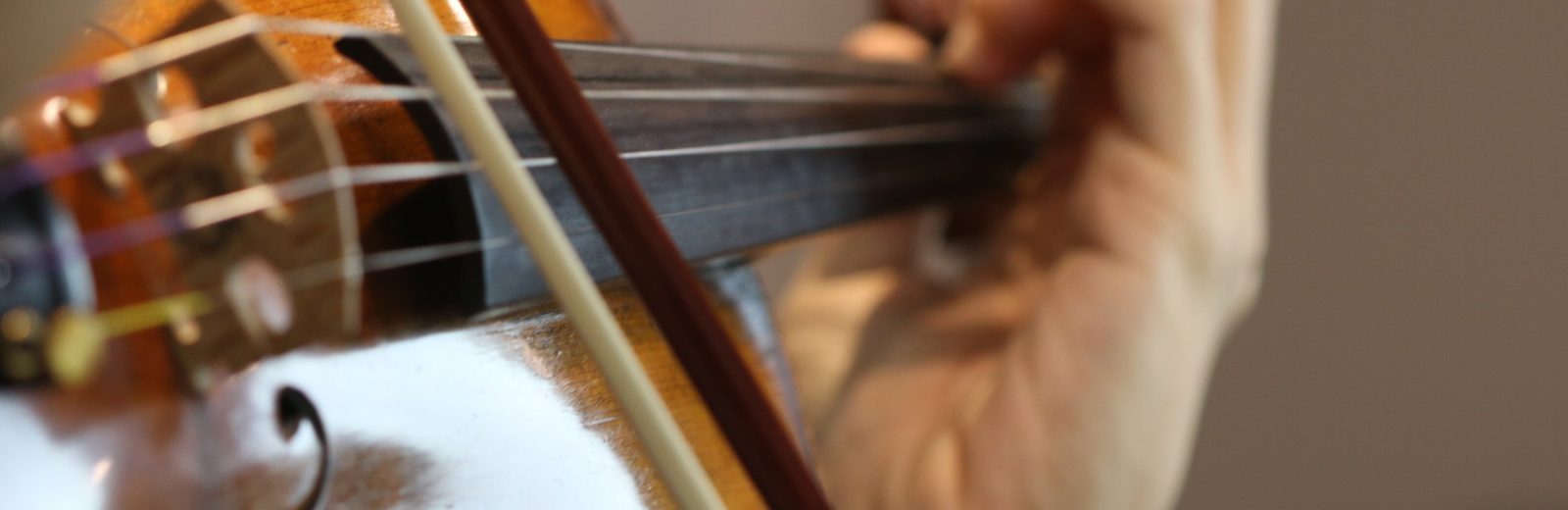 Close view of a violin, bow and left hand on the fingerboard